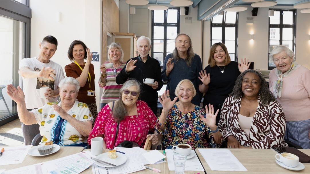 Together Co group waving at a community tea event